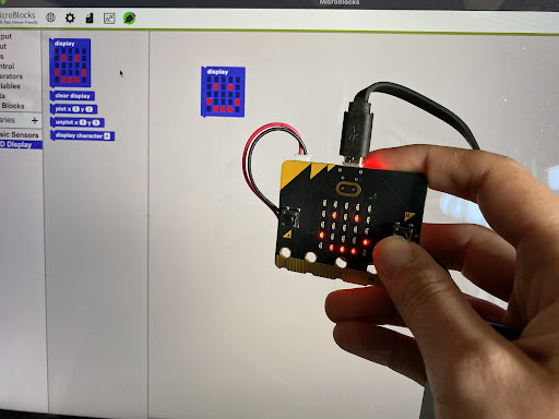 smiley face on a micro:bit next to computer code