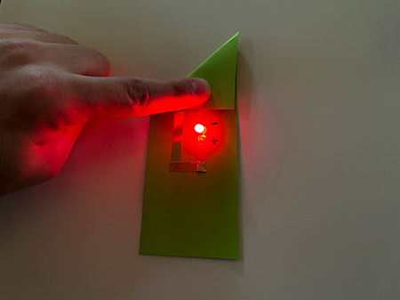 LED turns on when the paper corner is pressed on top of the battery